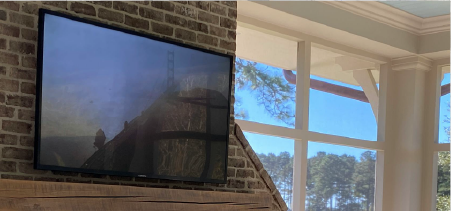 TV Mounted above a fireplace mantle on a brick wall