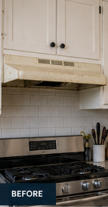 Before range hood installation: old white builder hood over a gas range with subway tile